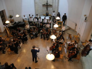 Kindersitzen in einem Kunstmuseum auf dem Boden und hören den Kuratoren zu.